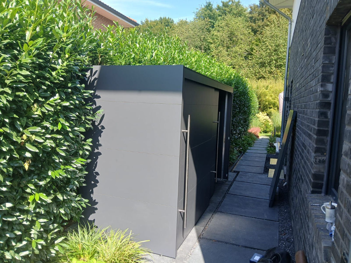 Moderner wetterfester Gartenschrank aus HPL in Anthrazit neben einem Wohnhaus im Garten